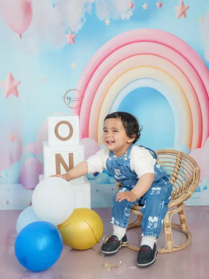 Pure delight! This candid photo captures a moment of laughter and play with balloons, showing the fun side of a first birthday session.