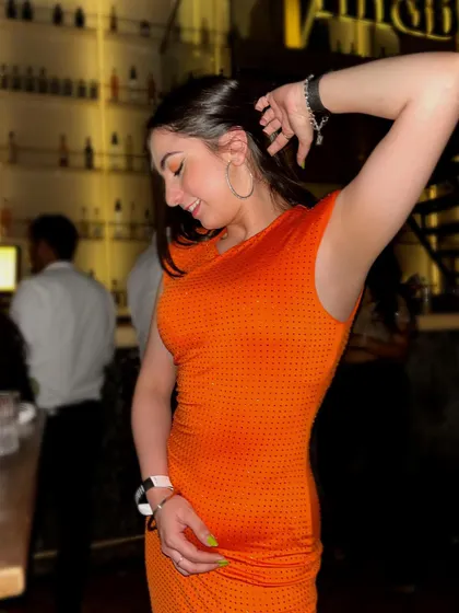 Made you look. A candid dancing shot in a bright orange bodycon dress, perfect for grabbing attention on a night out.