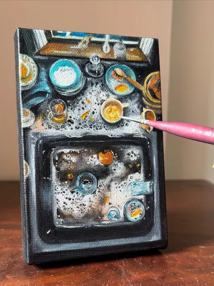 Adding the final touches to the miniature painting of a chaotic sink. The tiny brush allows for incredible detail, even on such a small canvas.