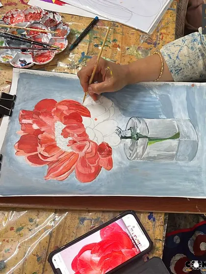 This student is painting a vibrant red flower in a glass vase, focusing on capturing the delicate texture of the petals and the transparency of the glass.