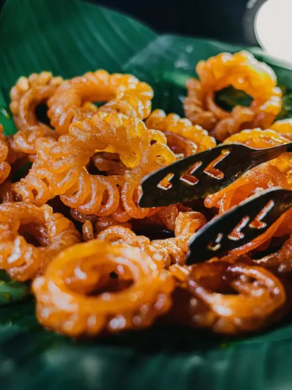 Taking "kuch meetha ho jaaye" very seriously with these crispy, golden imartis. Served fresh on a banana leaf, they are a traditional favourite that brings joy to any celebration.