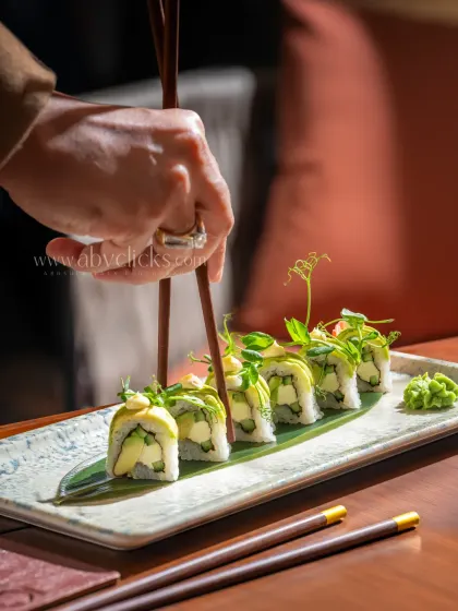 Another angle of the avocado sushi at Camo, with a hand adding a dynamic element to the scene.