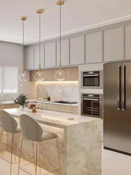 We designed this kitchen with a beautiful blend of light wood cabinetry and a marble-topped island with seating. Gold-accented pendant lights add a touch of elegance, while the integrated refrigerator maintains a seamless look.