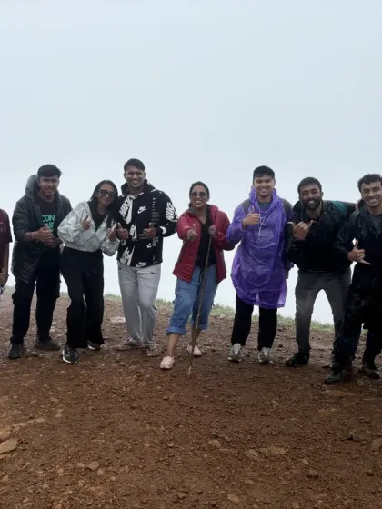 A happy group giving thumbs up at the summit, celebrating their successful trek together.