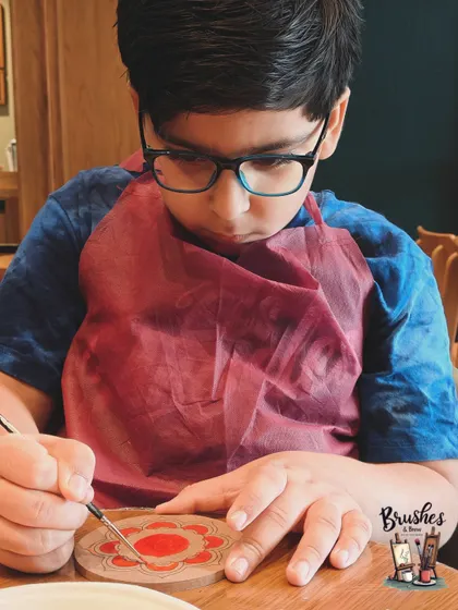Shaurya, one of our young regulars, meticulously painting a mandala on a coaster. His focus and passion are inspiring.