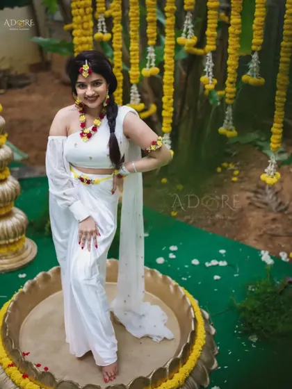 The bride is the center of attention in this lovely Haldi setup. The traditional elements, like the brass vessel and hanging floral strings, create a timeless and elegant scene.