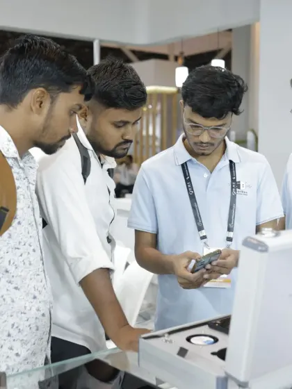 A group of young professionals gathers around a product demo, learning about a new smart device. The expo is a key educational platform for the next generation of integrators.