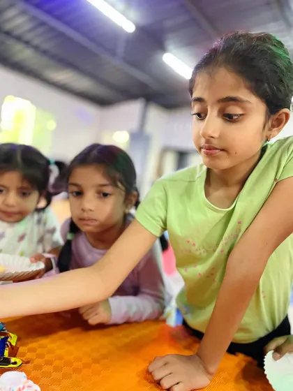 Childhood is about innocence and playfulness. Students gather around the table for party snacks and cake, a cherished part of any celebration.