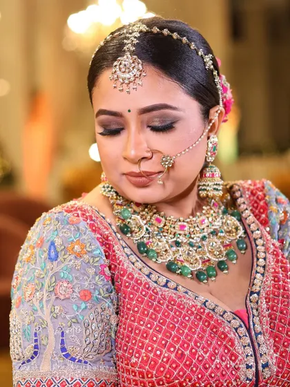 A detailed shot of the bride's intricate makeup and heavy Polki necklace with green stones, showcasing a classic and regal bridal style.