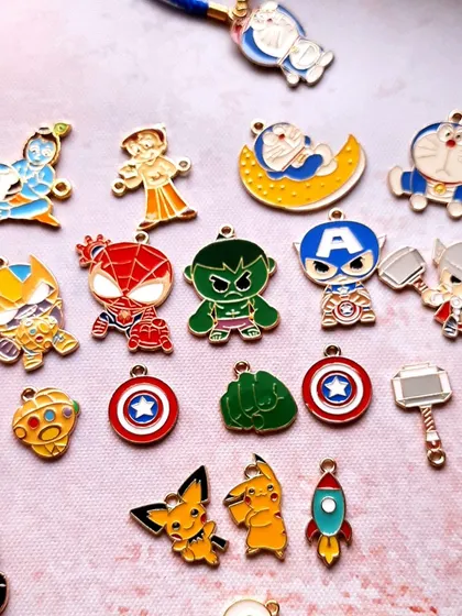 Unwrap joy with these kids' Rakhis featuring all their favorite characters. This image shows a wide variety of enamel charms, including superheroes like Spider-Man and Hulk, and cartoon icons like Doraemon and Pikachu.