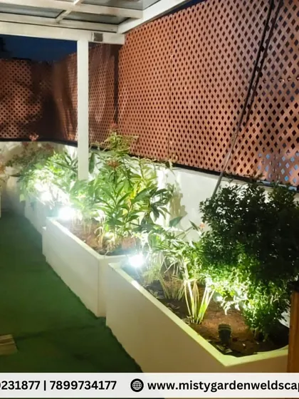 Spotlights inside the planters highlight the foliage at night, adding depth and drama to the terrace garden design.