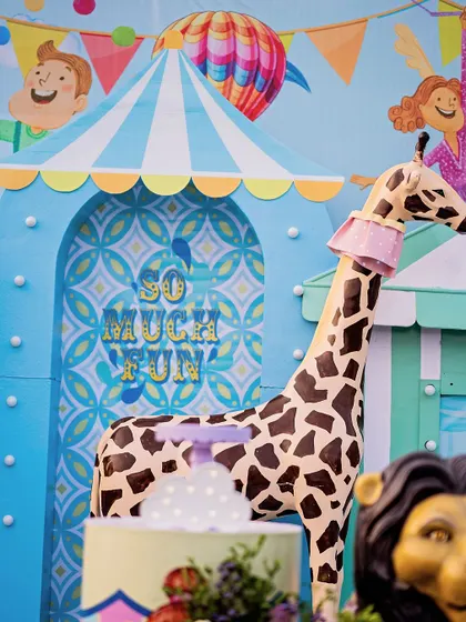A close-up of the "So Much Fun" archway, with a giraffe peeking through. The patterned backdrop and playful signage add layers of visual interest to the design.