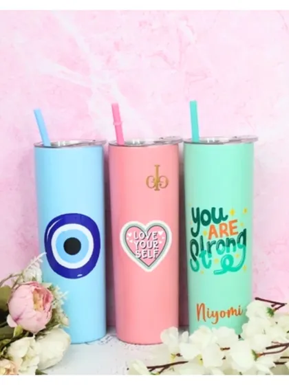 A trio of our personalized skinny tumblers in blue, pink, and mint. Each one is customized with a different design, including an evil eye, a "Love Your Self" heart, and a "You Are Strong" quote.