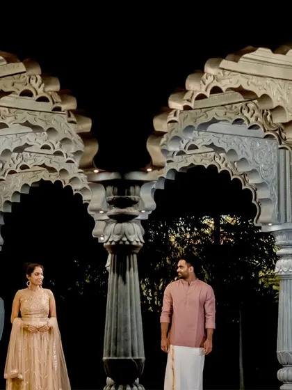 A wide shot of the couple standing under ornate arches, showcasing the grandeur of the location for their pre-wedding photos.