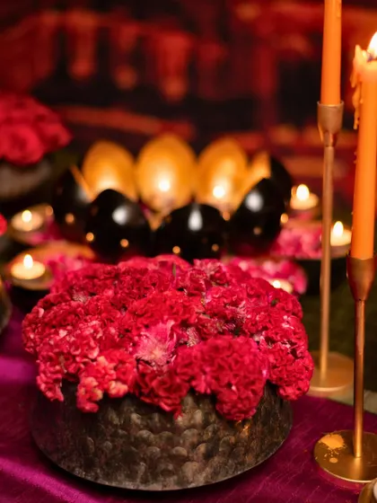 A 'Rang Saari' tablescape detail, with vibrant red carnations and glowing candles creating a festive mood.