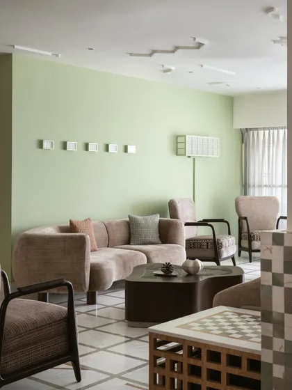 The living room in our Gingham Dreams project, where a soft, apple-green wall creates a fresh and inviting atmosphere. The furniture is a mix of modern forms and classic patterns.
