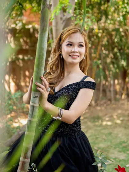 This shot captures the elegance of the black ballgown against a natural, green backdrop, showing its versatility for outdoor shoots.