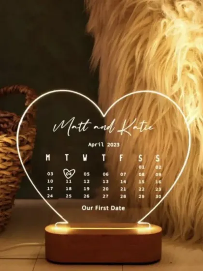 This heart-shaped acrylic LED lamp is personalized with a couple's names and a calendar marking their special first date.