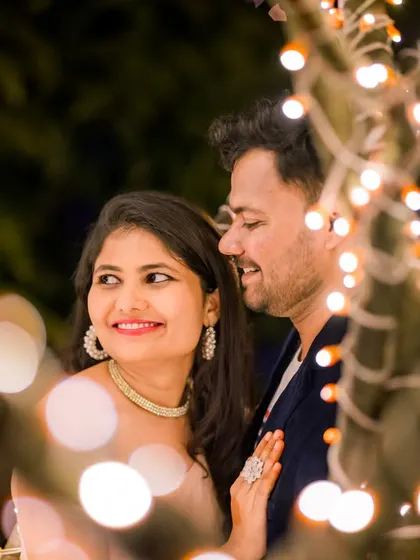 A candid, happy moment between a couple, captured through the beautiful bokeh of surrounding fairy lights. This shot feels natural and full of joy.