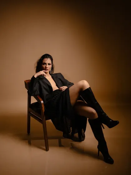 A powerful seated portrait from the 'FLOR' series. I styled an oversized black blazer with knee-high boots for a look that is both chic and commanding, using warm studio lighting to create a sophisticated mood.
