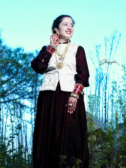 A candid, happy moment of a bride during her outdoor photoshoot. Her natural smile and the beautiful Himachali jewelry are the focus of this shot.