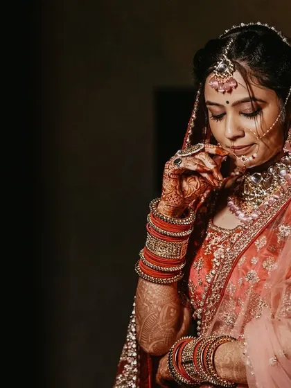 A stunning portrait of the bride, looking down at her intricate lehenga and jewelry in a moment of quiet reflection.