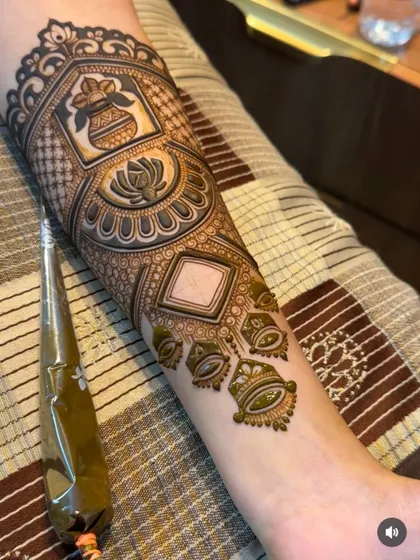 This Karva Chauth special design features a sacred kalash and a lotus, showcasing my ability to create symbolic and festive mehandi. The henna cone shows the tool I use for this fine linework.
