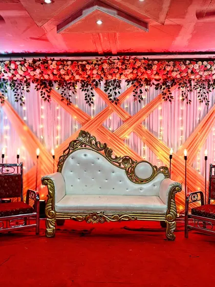 Another affordable stage decoration option at just 12,000/-. This design uses a combination of floral arrangements and draped fabric with fairy lights to create a festive and traditional wedding stage.