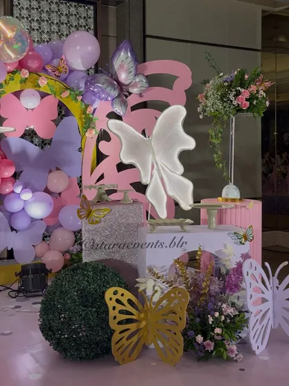 This detailed shot showcases the variety of butterfly props used, from large 3D cutouts in gold and white to smaller accents, all part of the layered decor.