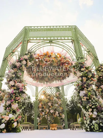 A closer look at the top of the gazebo mandap, where a floating floral chandelier and soft pink draping add a touch of softness against the sky.