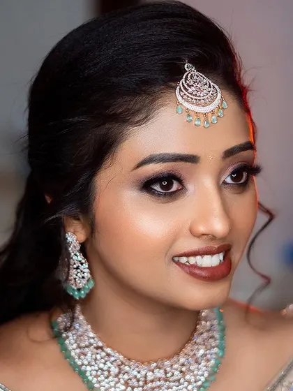 A beautiful, candid close-up of the bride's smiling face, capturing the joy of her special day. The focus is on her expression and diamond jewelry.