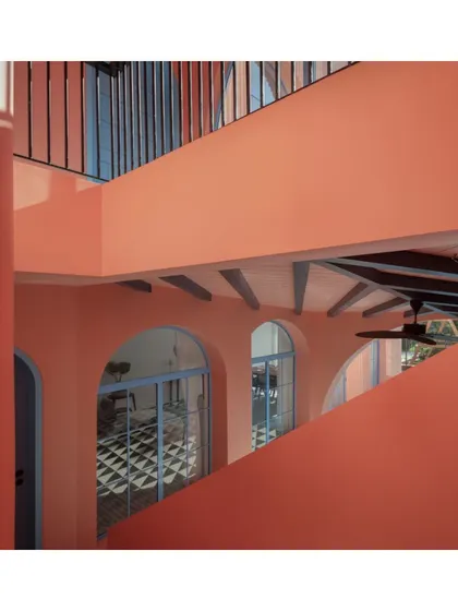 The interlocking forms and levels of the Baia Villas create a complex and engaging journey through the space. This view captures the relationship between the upper balcony and the ground-floor veranda, connected by the unifying peach facade.