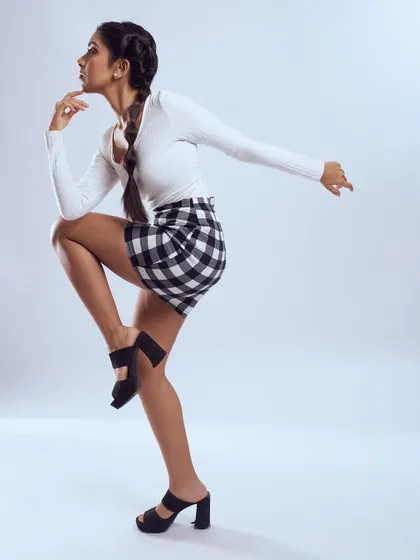 A full-length shot of a playful, preppy look. The bubble braids and clean makeup create a youthful and energetic feel.