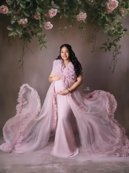 A soft and romantic portrait with a flowing pink gown and a floral backdrop. This studio look is perfect for capturing the gentle and beautiful side of expecting.