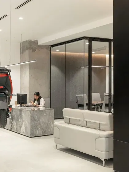 The suspended electric scooter is visible from the reception desk, making a powerful statement about the company's product-centric culture. The minimalist interior, with its clean lines and neutral palette, ensures the vibrant red scooter remains the undeniable focal point.