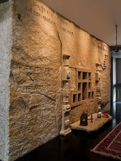 This contemporary mandir features a wall of naturally split granite, with scriptures engraved directly into the stone and niches carved out for sacred murtis. It is a powerful example of integrating spiritual practice with raw, architectural materials.