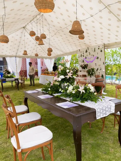 A large tented area for an outdoor event, with elegant tables and chairs set up on the grass. This allows for a comfortable dining experience regardless of the weather.