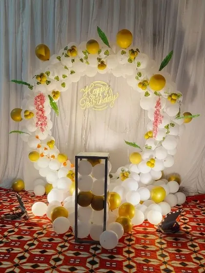 A classic white and gold balloon ring set up indoors. This decoration is perfect for creating a dedicated photo corner in any room, complete with a neon sign and floral accents.