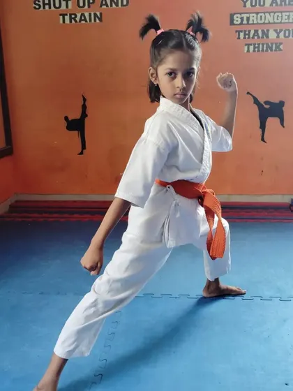A young karate student in a classic fighting pose, ready for action.