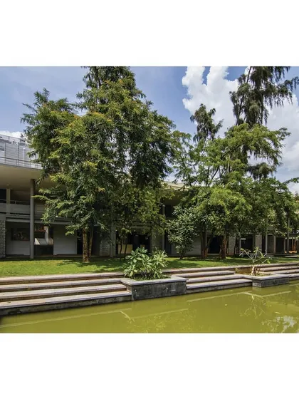 The new building seen from across the water, nestled within the lush greenery of the campus.