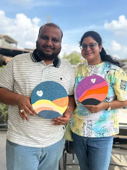 A happy couple showing off the complementary paintings they created at a private workshop. It's a wonderful activity for date night.
