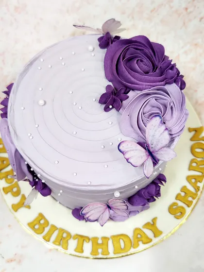 We create a dreamy vision with this lavender butterfly cake. A cascade of purple buttercream roses and delicate, edible butterflies adorns the textured lavender frosting, accented with tiny pearls for a touch of magic and elegance.