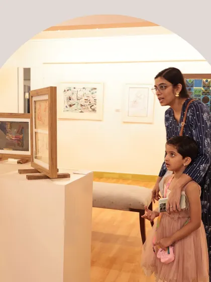 A mother and daughter look closely at a series of small sketches, sharing an educational moment.