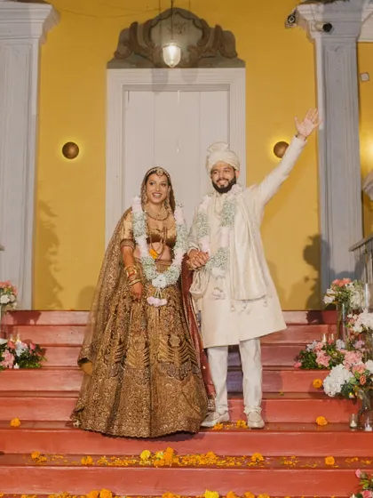 The happy couple waving to their guests from the steps of the venue, a classic and joyful wedding portrait.