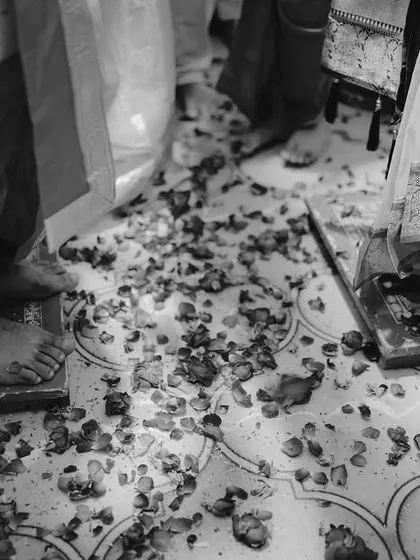 A detail shot of the couple's feet during a ritual, the floor scattered with petals, symbolizing their sacred steps.