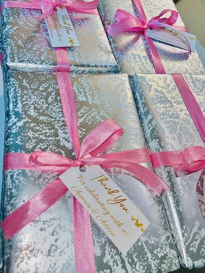These wedding favors for Apoorva and Aditya feature a brass photo frame and custom candle, wrapped in elegant silver and pink.