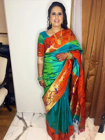 A full-length photo of Mrinal's reception look. The vibrant colors of her saree are balanced with glowing makeup and a bright smile.