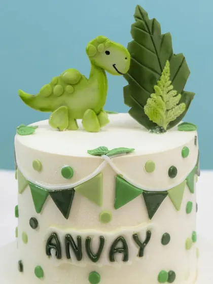 A close-up of the cute, handcrafted dinosaur topper, perfect for a prehistoric party.