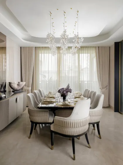 A gathering in grace. We designed this dining space for shared meals and stolen moments, under a canopy of crystal blooms. The neutral palette of the chairs and walls creates a calm, elegant atmosphere.