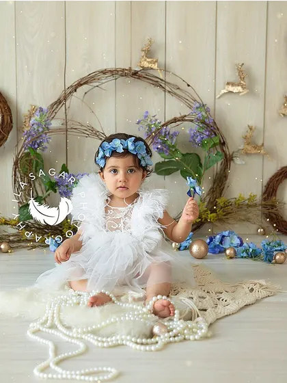 A lovely sitter session portrait with a rustic, floral wreath background. Her serious expression and beautiful dress create a timeless image.